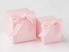 Two pink gift boxes with ribbons on a light gray background