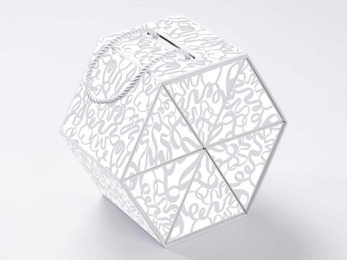 White geometric card box with cut-out patterns on a light gray background