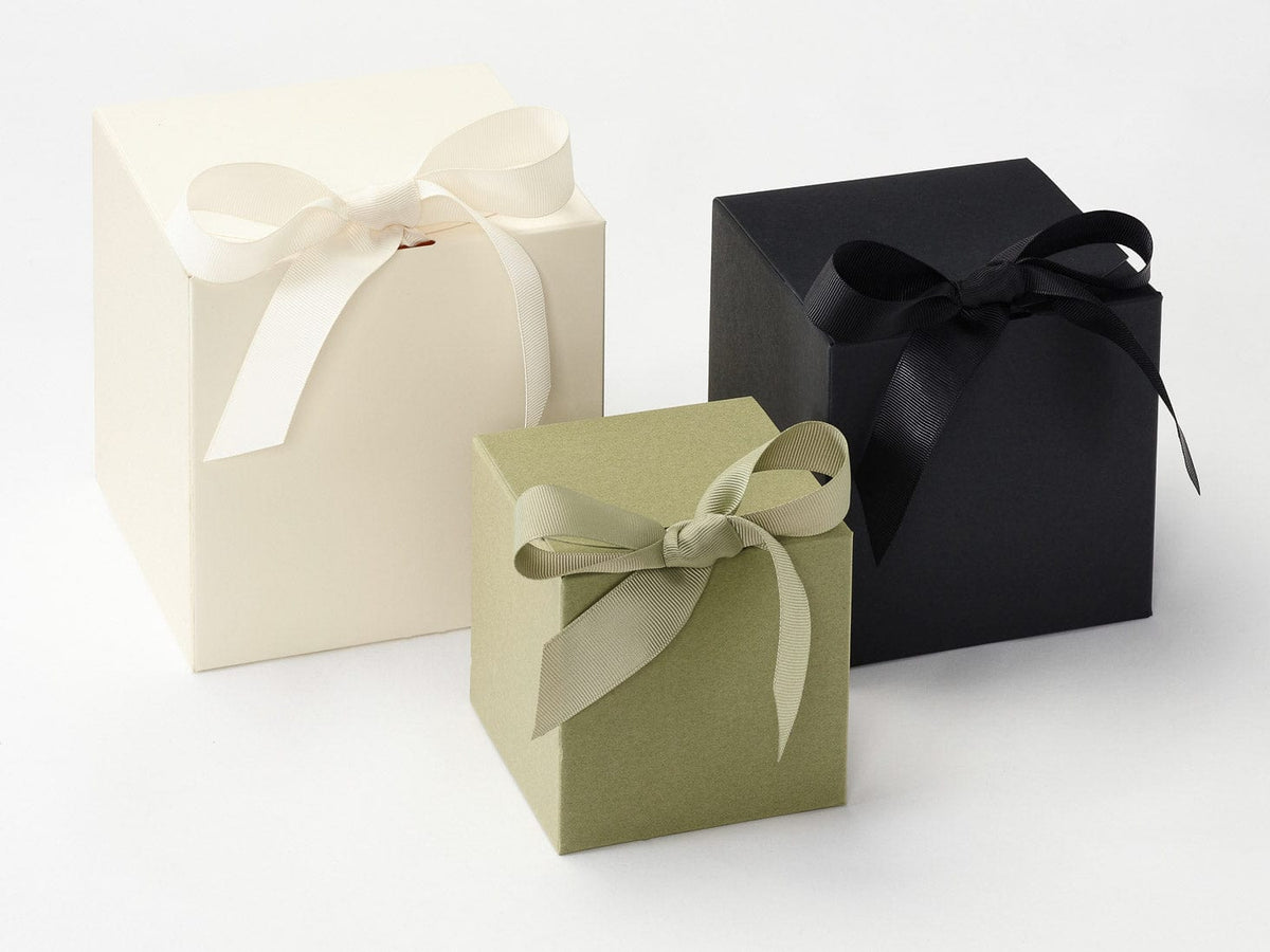 Three gift boxes in Ivory, Sage green, and Black with ribbons on a white background