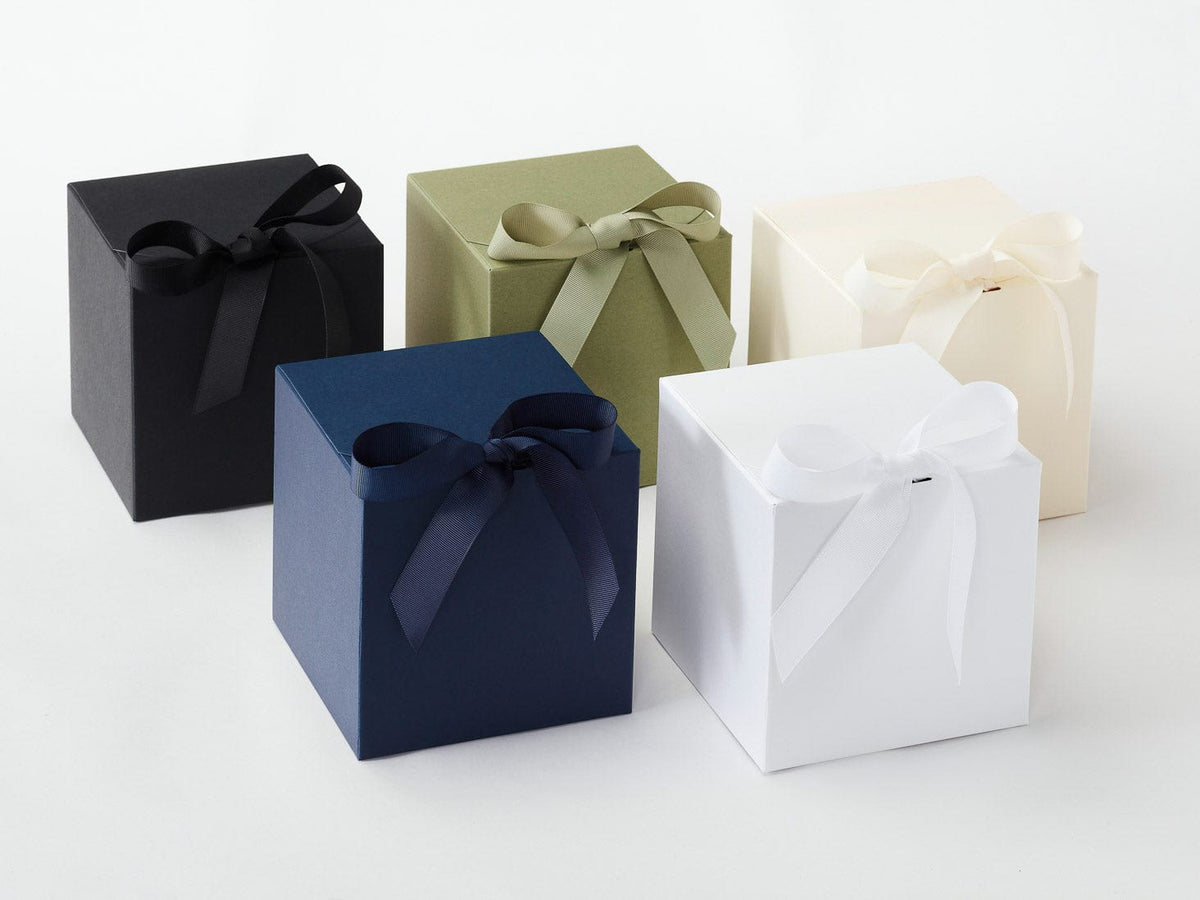 Four softbox gift boxes in black, green, blue, and white with ribbons on a white background